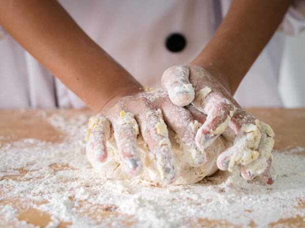 Des mains d'enfant entrain de malaxer de la pate lors d'un cours de cuisine