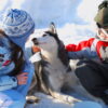 Les enfants caresse un chien de traineau dans la neige