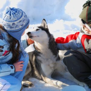 Deux enfants avec un chien sur la neige