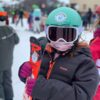 Petite fille prête pour son cours de ski, skis à la main