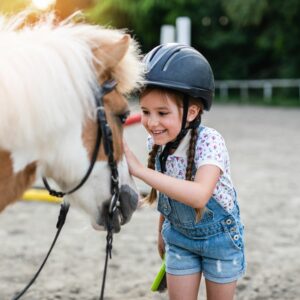 Petite fille caressant un poney