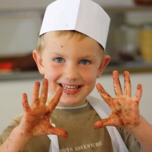 Petit garçon souriant en atelier cuisine à la colo Neige et Soleil