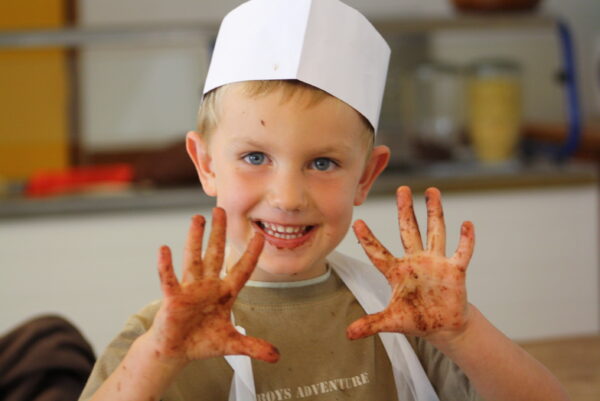 Petit garçon souriant en atelier cuisine à la colo Neige et Soleil