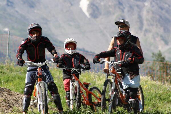Deux enfants et le moniteur avec leur equipement pour descendre des circuits en BMX