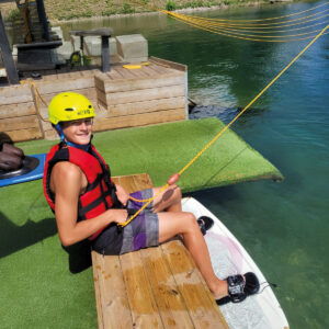 Un ados souriant, équipé et prêt à faire du wakeboard sur un lac avec son centre de vacances Neige et Soleil