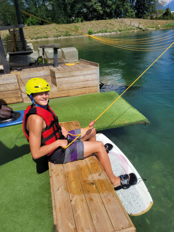Un ados souriant, équipé et prêt à faire du wakeboard sur un lac avec son centre de vacances Neige et Soleil