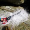 Un ados fais un toboggan dans une rivière de canyoning