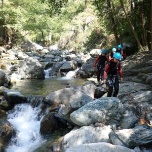 Groupe d'adolescents entièrement équipé pratiquant le Canyoning en Savoie lors d'une colo neige et soleil