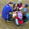 Groupe d'enfants avec leur animateur dans un champ de la colo lors d'une activite